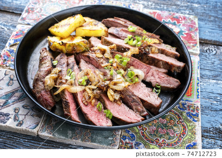 Barbecue dry aged wagyu flank steak with pineapples and onion rings 74712723