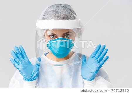 Covid-19, preventing virus, health, healthcare workers and quarantine concept. Close-up female doctor or nurse in personal protective equipment, rubber gloves and respirator showing hands 74712820