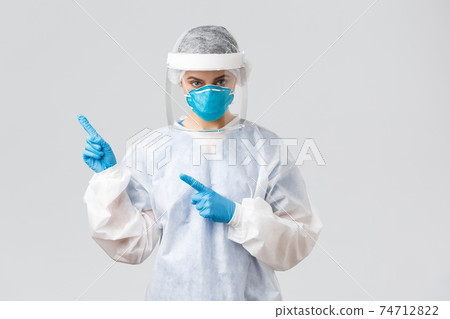 Covid-19, preventing virus, health, healthcare workers and quarantine concept. Professional doctor or nurse fighting ncov, coronavirus, wear protective suit and respirator, pointing fingers left 74712822