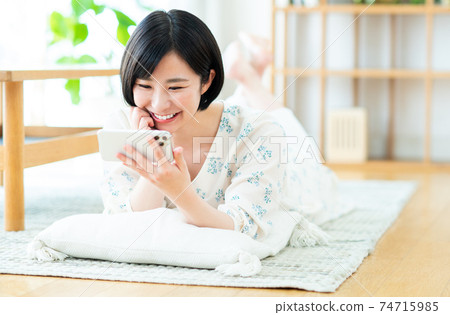 A young woman watching a video on her smartphone A young woman watching a video on her smartphone 74715985