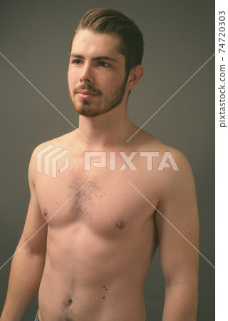 Young handsome bearded man shirtless against gray background Young handsome bearded man shirtless against gray background 74720303