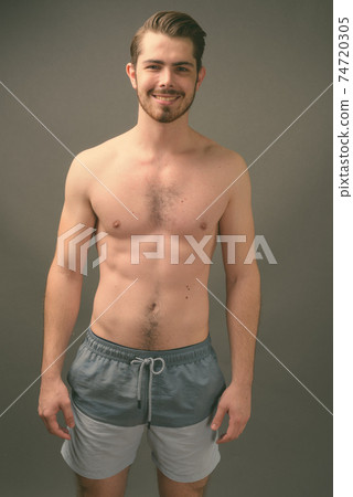 Young handsome bearded man shirtless against gray background Young handsome bearded man shirtless against gray background 74720305