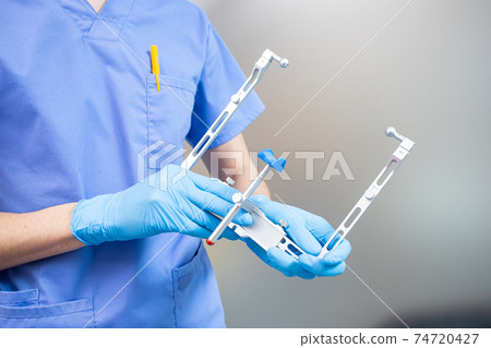 The dentist holds a facial bow in his hands. Orthopedic instrument. Modern technologies The dentist holds a facial bow in his hands. Orthopedic instrument. Modern technologies 74720427