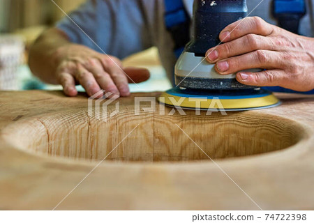 Woodworker sanding wooden furniture element in workshop Woodworker sanding wooden furniture element in workshop 74722398