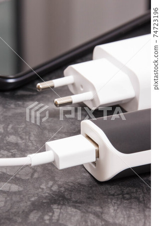 Black smartphone with connected plug of external powerbank. Mobile phone charging 74723196