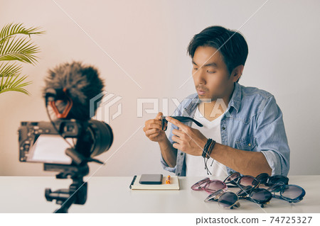 Front Left Asian Vlogger or Blogger Review Fashion Glasses by Video Recording in Vintage Tone Front Left Asian Vlogger or Blogger Review Fashion Glasses by Video Recording in Vintage Tone 74725327