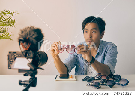 Front Asian Vlogger or Blogger Show Pink Fashion Glasses and Recording Video in Vintage Tone Front Asian Vlogger or Blogger Show Pink Fashion Glasses and Recording Video in Vintage Tone 74725328