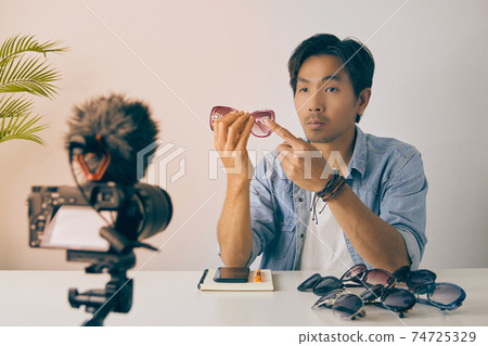 Front Asian Vlogger or Blogger Review Pink Fashion Glasses and Recording Video in Vintage Tone Front Asian Vlogger or Blogger Review Pink Fashion Glasses and Recording Video in Vintage Tone 74725329