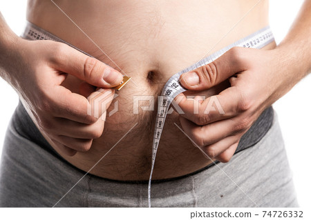 A man in the process of measuring his waist A man in the process of measuring his waist 74726332