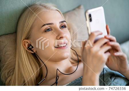 Girl happens to music in earphones and smiles 74726336