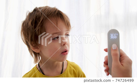 using infrared thermometer to measure child's body temperature 74726499