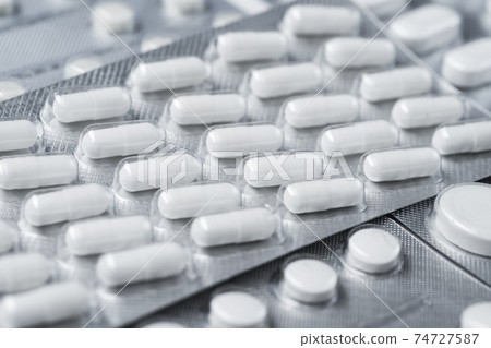 Pills in a blister pack. scattered pills and tablets in package isolated on white background 74727587