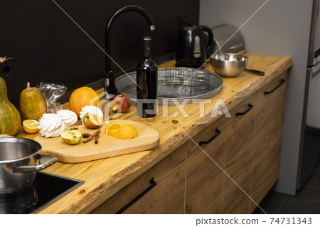 Oak kitchen worktop on kitchen with a sink, cookstove and food ingredients, bottle and kitchen facilities. Practical using of wooden worktop. Modern interior. Cooking. 74731343