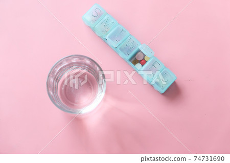top view of pill box and glass of water on pink top view of pill box and glass of water on pink 74731690