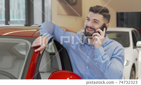 Bearded man talking on his phone at car dealership 74732323