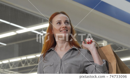 Attractive woman looking around in the mall while shopping Attractive woman looking around in the mall while shopping 74733096