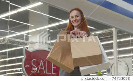 Cheerful woman smiling to the camera holding her shopping bags 74733098