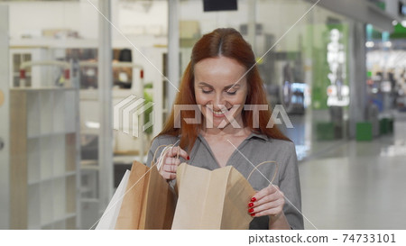 Charming woman looking into her shopping bag at the mall Charming woman looking into her shopping bag at the mall 74733101