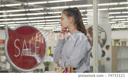 Young woman looking at the display of a store at the mall 74733121