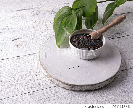 Black quinoa seeds and scoop in bowl on white table Black quinoa seeds and scoop in bowl on white table 74733278