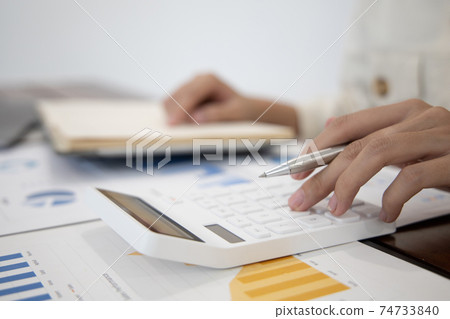 Head of accounting is recording the company's financial growth statistics using graphs as a reference for reviewing and analyzing the results, Taking notes and analyzing data graphs in office. 74733840