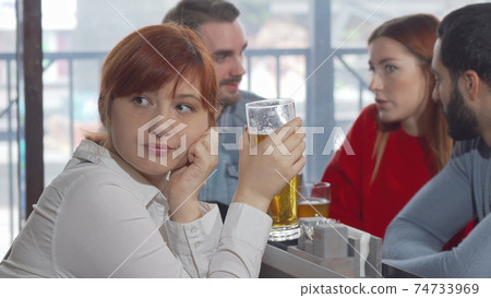 Sad woman drinking beer at the pub 74733969