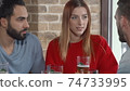 Sliding shot of a group of young people chatting over glass of beer at the pub 74733995