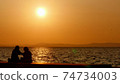 Silhouette of couple in love at sea in golden and beautiful sunset. Young and romantic couple enjoying. 74734003