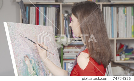 Beautiful young woman painting a picture at art workshop Beautiful young woman painting a picture at art workshop 74734536