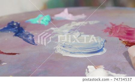 Unrecognizable female artist mixing paint on a palette Unrecognizable female artist mixing paint on a palette 74734537
