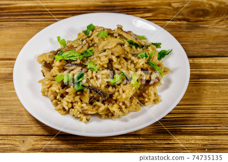 Tasty risotto with mushrooms on wooden table 74735135