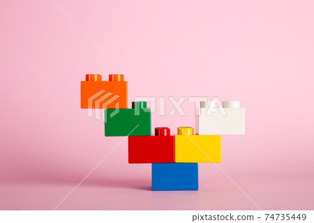 Color plastic building blocks on pink background 74735449