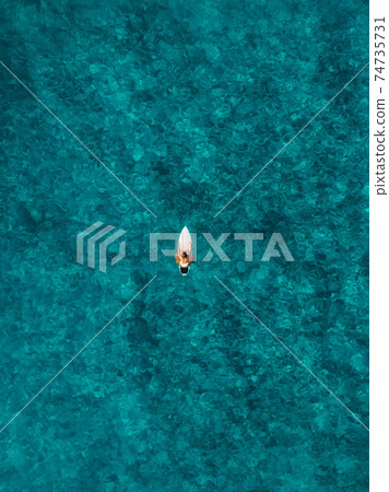 Surfer woman with surfboard in blue ocean. Aerial view with surf girl Surfer woman with surfboard in blue ocean. Aerial view with surf girl 74735731