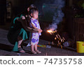 Parent and child holding handheld fireworks 74735758