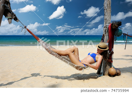 Woman in hammock on beach Woman in hammock on beach 74735994