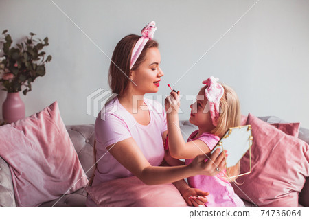 Charming little girl helps to apply make-up to her mothers face 74736064