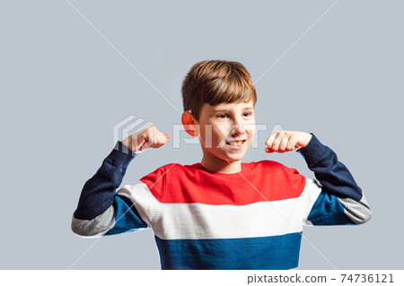 the smiling boy with raised hands demonstrates his muscular the smiling boy with raised hands demonstrates his muscular 74736121