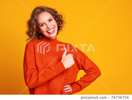 Delighted young woman gesturing thumbs up OK 74736756