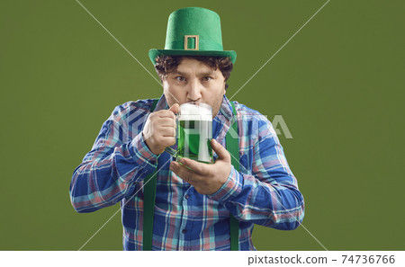 Young Irish man in leprechaun party hat drinking green beer on Saint Patrick's Day Young Irish man in leprechaun party hat drinking green beer on Saint Patrick's Day 74736766