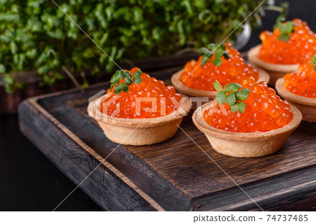 Delicious fresh red caviar on a dark concrete table Delicious fresh red caviar on a dark concrete table 74737485