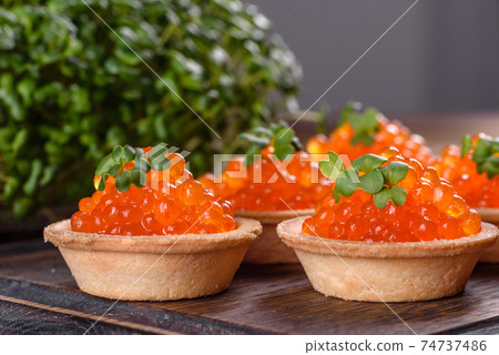 Delicious fresh red caviar on a dark concrete table Delicious fresh red caviar on a dark concrete table 74737486