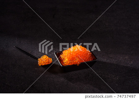 Delicious fresh red caviar on a dark concrete table Delicious fresh red caviar on a dark concrete table 74737497