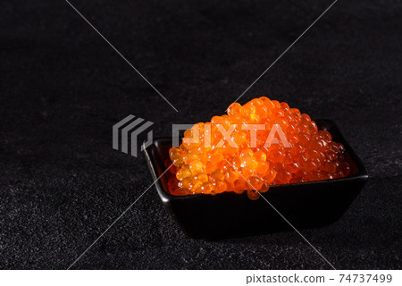 Delicious fresh red caviar on a dark concrete table Delicious fresh red caviar on a dark concrete table 74737499