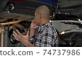 Stressed young man talking on the phone at the garage 74737986