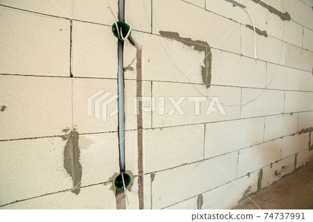 New electrical wiring installation, plastic boxes and electrical cables for future outlet sockets on the wall, renovation concept. New electrical wiring installation, plastic boxes and electrical cables for future outlet sockets on the wall, renovation concept. 74737991