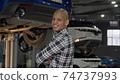 Cheerful African man smiling to the camera standing at cars workshop 74737993