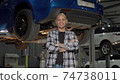 Happy handsome car repairman smiling to the camera at his garage 74738011