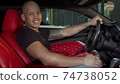 Happy handsome African man smiling to the camera sitting in his sports car 74738052