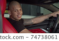 Cheerful handsome African man smiling to the camera while sitting in his car 74738061