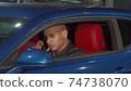Handsome young man talking on the phone sitting in his car 74738070